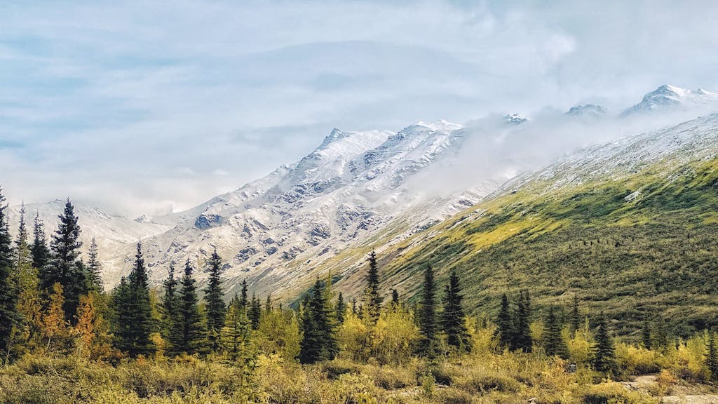 Breathtaking view of Alaskan mountains with autumn foliage and partial fog cover.